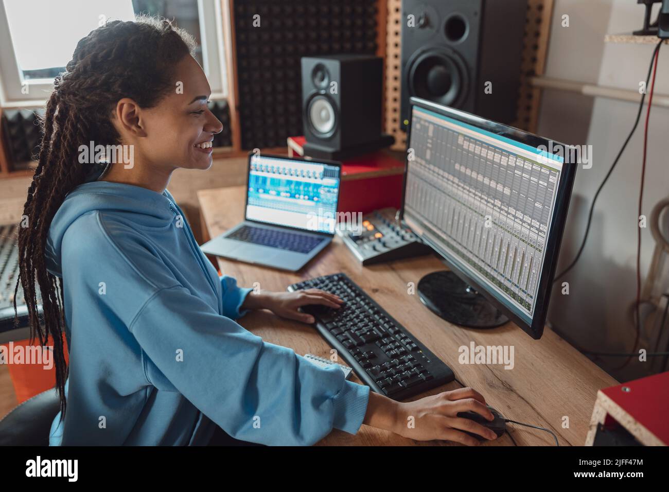Bella giovane ed elegante ingegnere audio afro-americano e produttore in abbigliamento casual lavorando in studio di registrazione musicale creando canzone cool Foto Stock