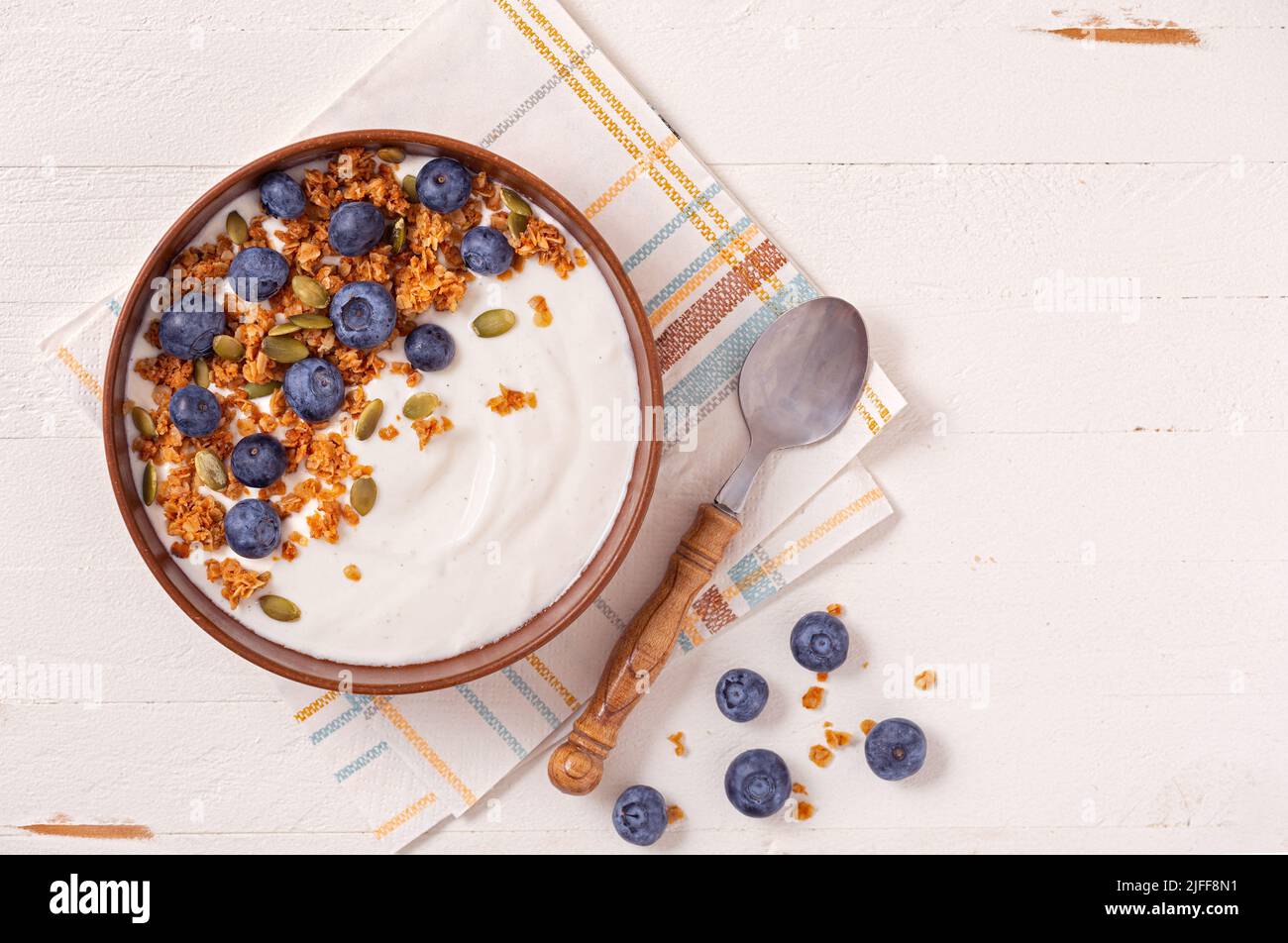 Vista dall'alto di yogurt alla vaniglia e mirtilli su una superficie di legno bianco; spazio copia Foto Stock
