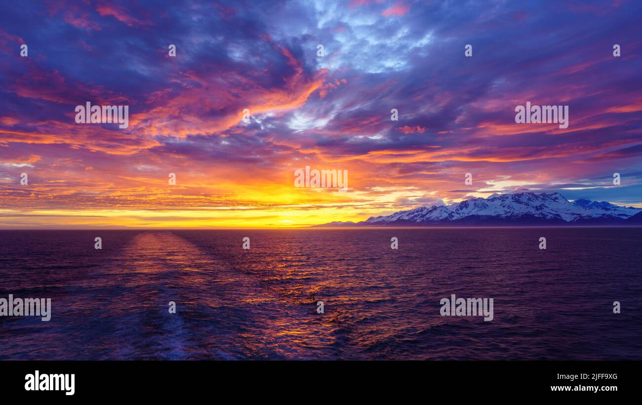 Sole all'orizzonte dalle montagne e Mount Fairweather dal Glacier Bay National Park in Alaska Foto Stock