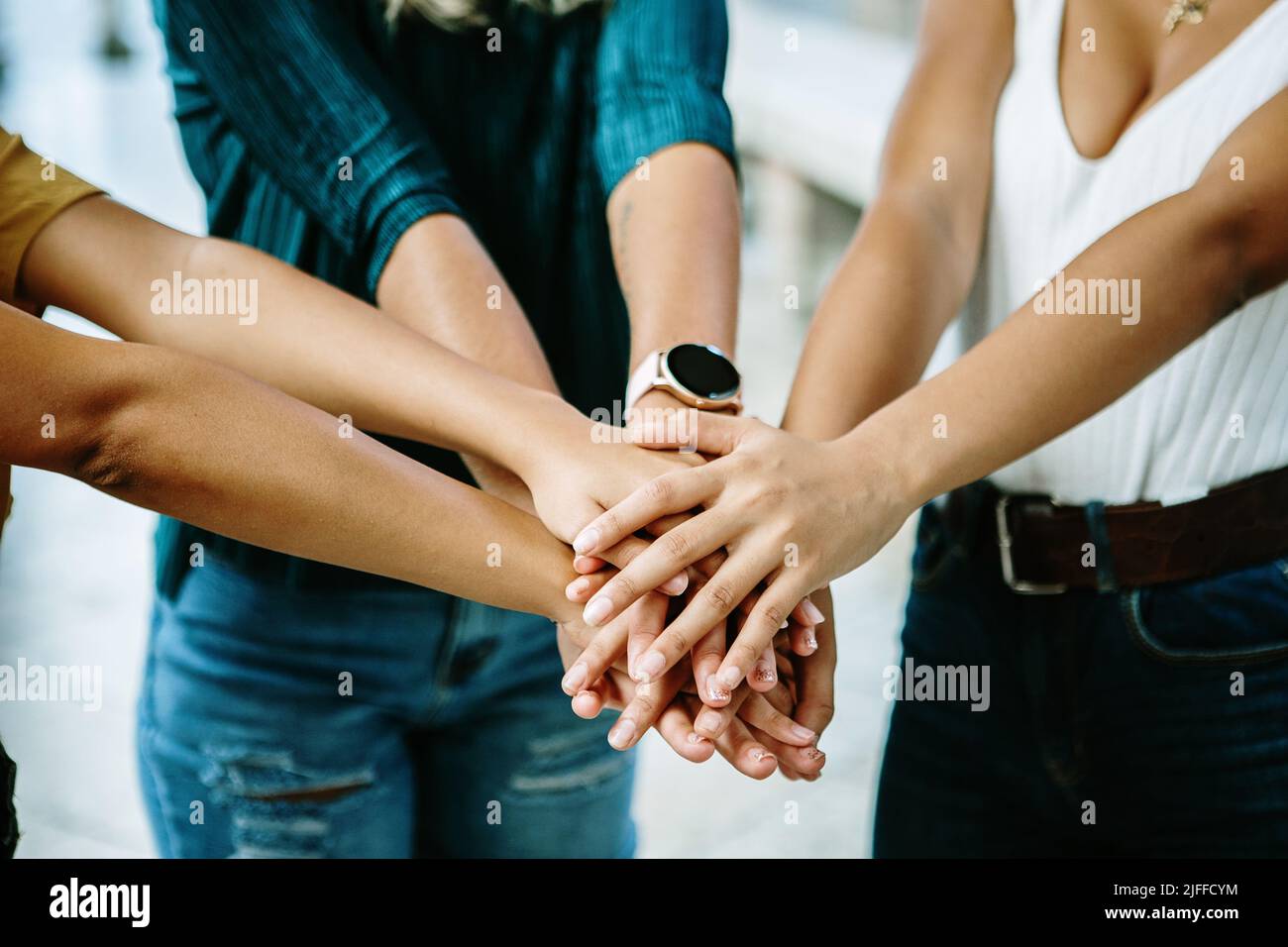 Amicizia femminile unita con tre donne multirazziale impilamento mani all'aperto Foto Stock