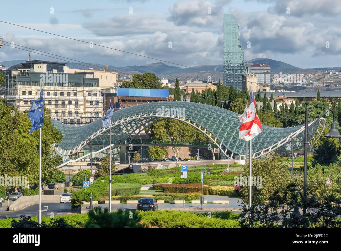 Paesaggio urbano di Tbilisi con moderno Ponte della Pace e bandiera georgiana nazionale, Georgia. Foto Stock