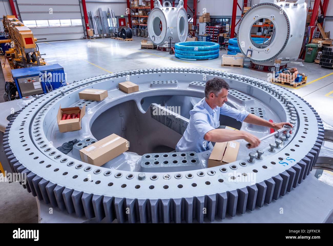 Rostock, Germania. 30th giugno 2022. Il dipendente Tony Maas lavora sul cuscinetto azimuth, il cuscinetto rotante di una turbina eolica, nella sala di montaggio del produttore di turbine eoliche eno Energy. ENO Energy sviluppa e costruisce attualmente con circa 250 dipendenti e dal 2014 ha fornito un totale di 380 turbine eoliche. Credit: Jens Büttner/dpa/Alamy Live News Foto Stock