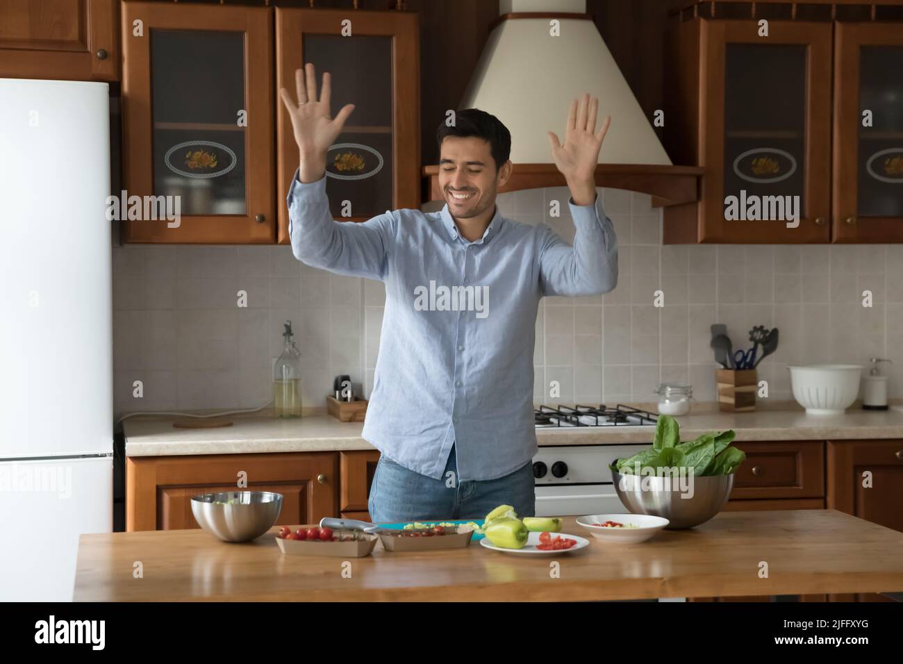 Il giovane bel latino si sposta alla musica che cucina in cucina Foto Stock