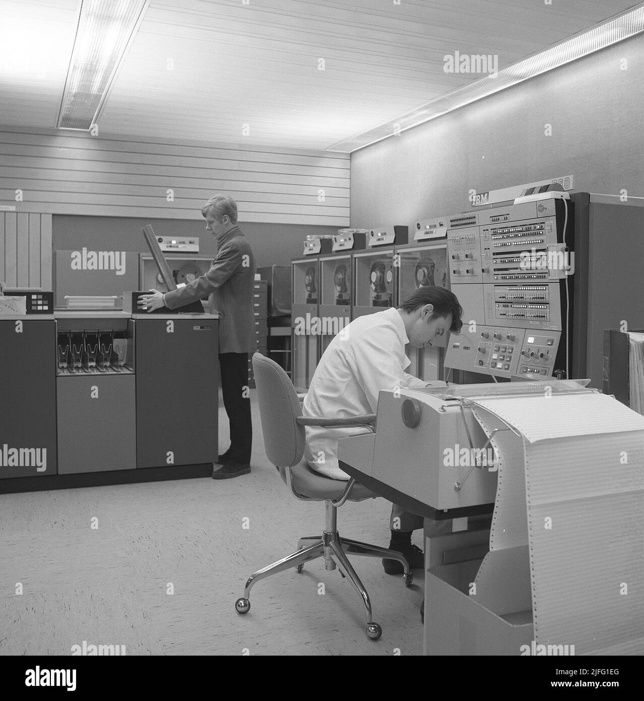 Nel 1960s. All'interno di una stanza con computer e persone sul lavoro di maneggiarli e registrare e leggere le informazioni. Un segno sopra il computer mainframe dice IBM 360. IBM System 360 è stato spesso visto nella serie televisiva americana Mad Men. Foto scattata 1965 Kristoffersson Ref DY128-9 Foto Stock
