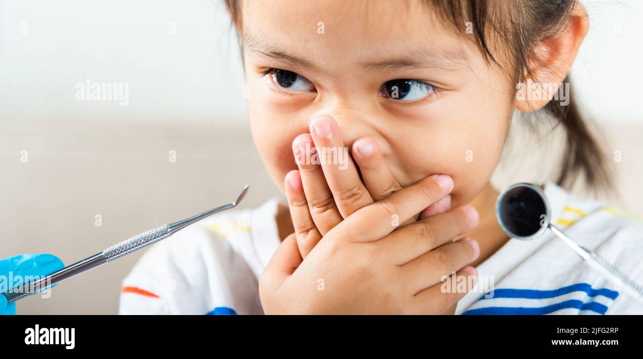 Esame dentale del bambino. Il medico esamina la cavità orale del bambino usa lo specchio della bocca per controllare la cavità dei denti ma la bocca della copertura della bambina non ha bisogno di controllare s Foto Stock