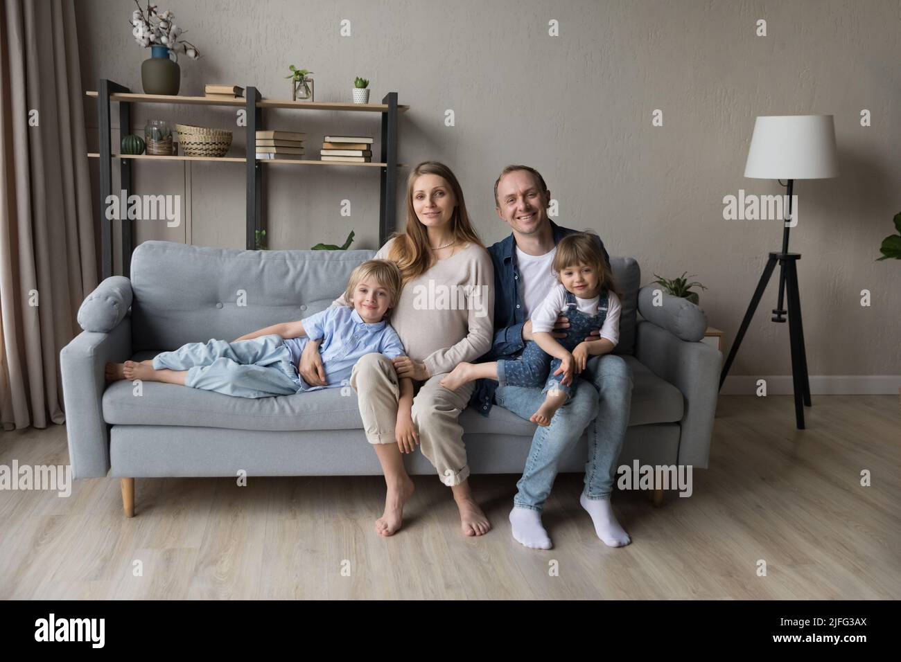 Coppia con bambini in posa per foto di famiglia seduti sul divano Foto Stock