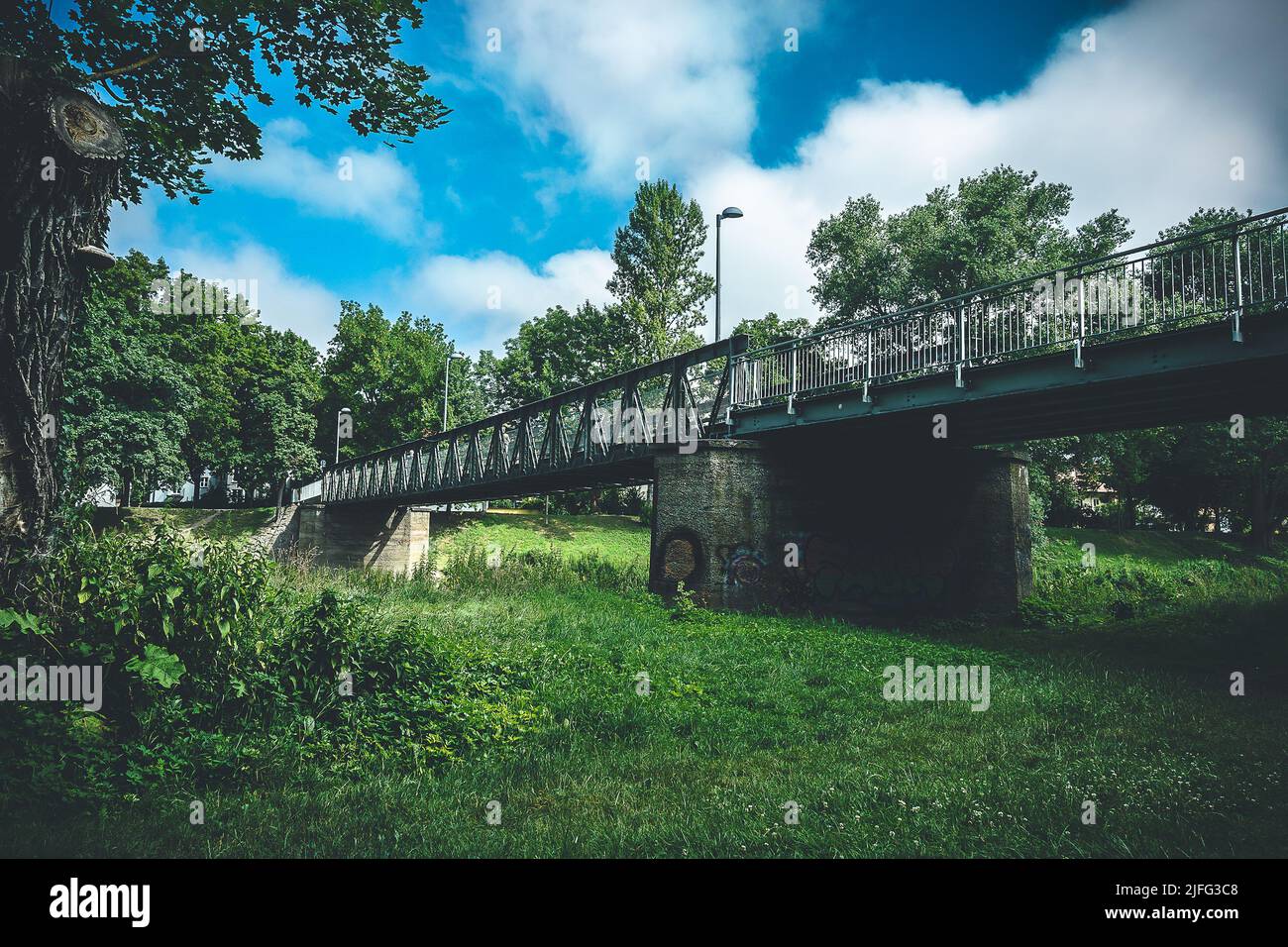 Una passerella in ferro attraversa le braccia del Danubio e attraversa un bellissimo parco Foto Stock