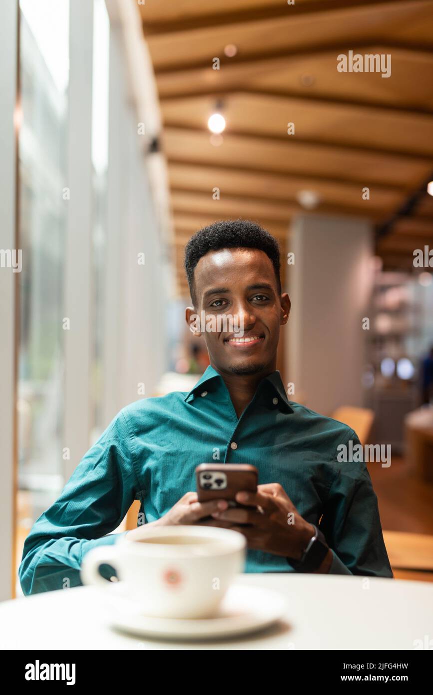 Ritratto di bel giovane uomo nero in caffetteria Foto Stock