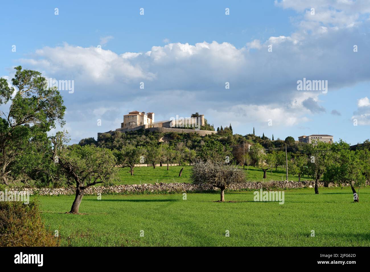 Mallorca - Vista della chiesa di pellegrinaggio Santuari de Sant Salvador a Artà, prati e alberi in primo piano, tempo soleggiato con una leggera nuvola coperta Foto Stock