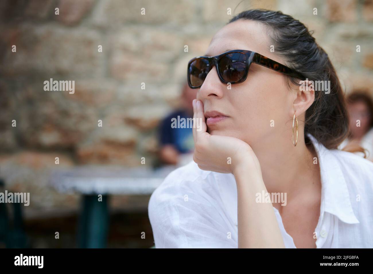 Donna bruna di età media con occhiali da sole e atteggiamento premuroso Foto Stock