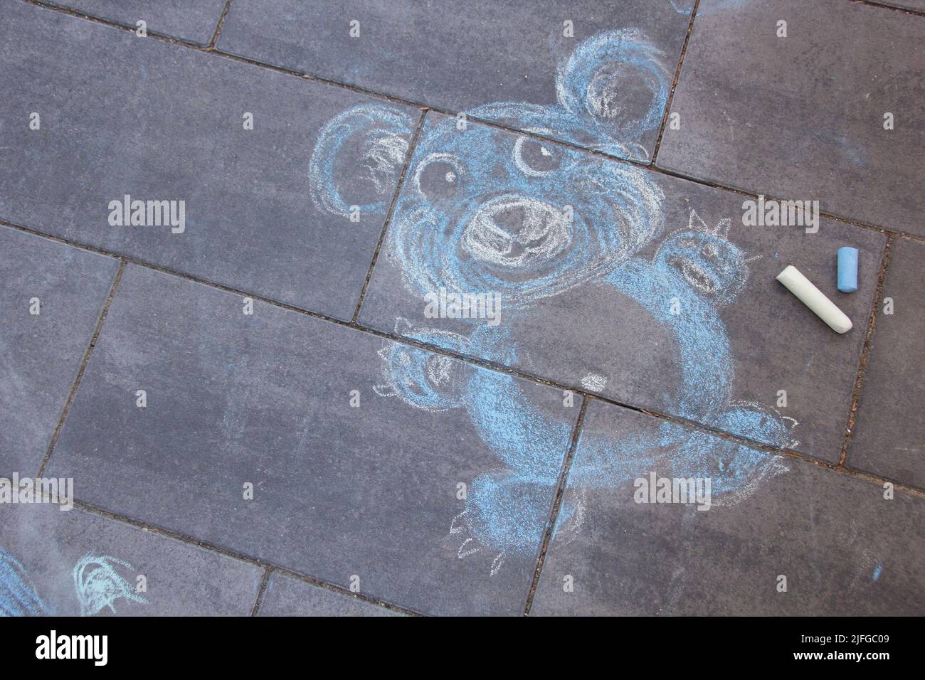 Carino bambino blu orsacchiotto gesso pittura sulla strada con blu e bianco gesso pastelli Foto Stock