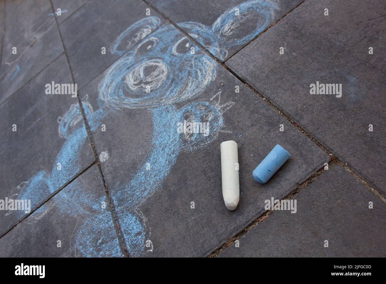 Carino bambino blu orsacchiotto gesso pittura sulla strada con blu e bianco gesso pastelli Foto Stock