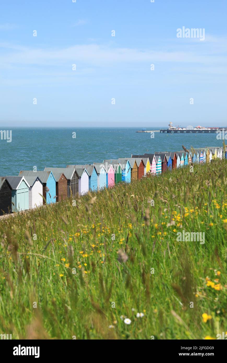 Colorate capanne sulla spiaggia a Herne Bay, con il molo in lontananza, nel nord Kent, Regno Unito Foto Stock