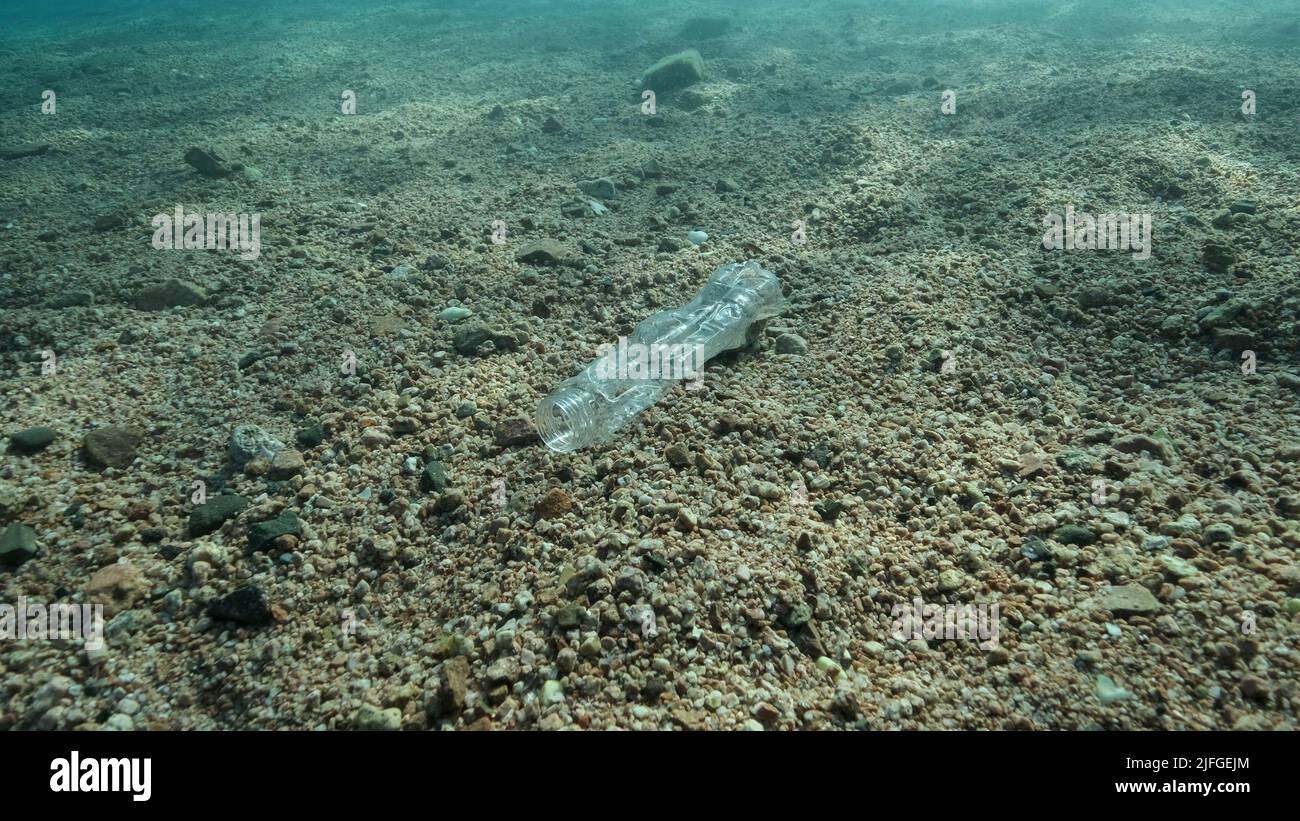 Primo piano, una bottiglia di plastica si trova sul fondo marino ai raggi del sole, nella zona costiera sulla spiaggia. Inquinamento plastico dell'Oceano. Mar Rosso, Egitto Foto Stock