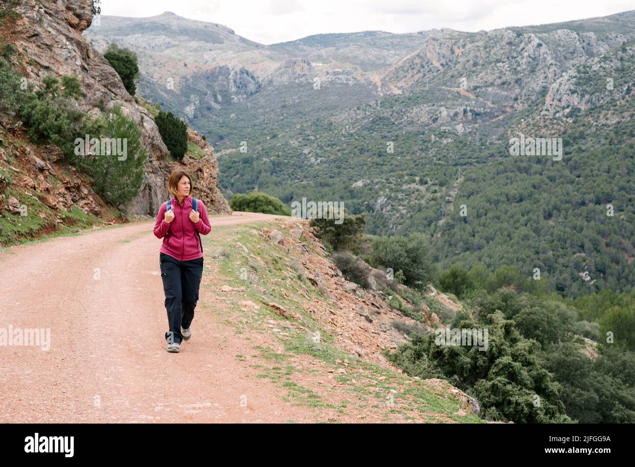 Donna che cammina su una pista fuoristrada con splendide viste naturali del mediterraneo. Foto Stock