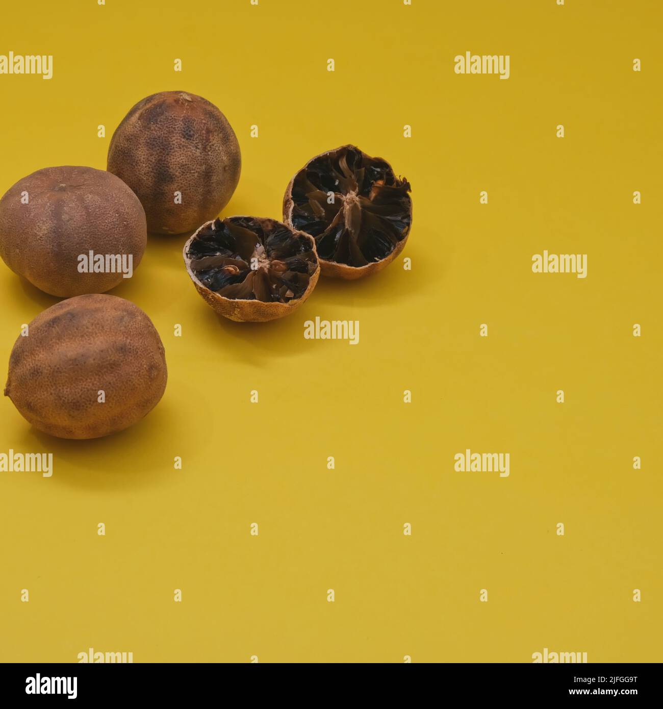Loomi organici essiccati al sole o lime nere, limone nero, limoni di Omani su sfondo giallo. Cucina mediorientale Foto Stock