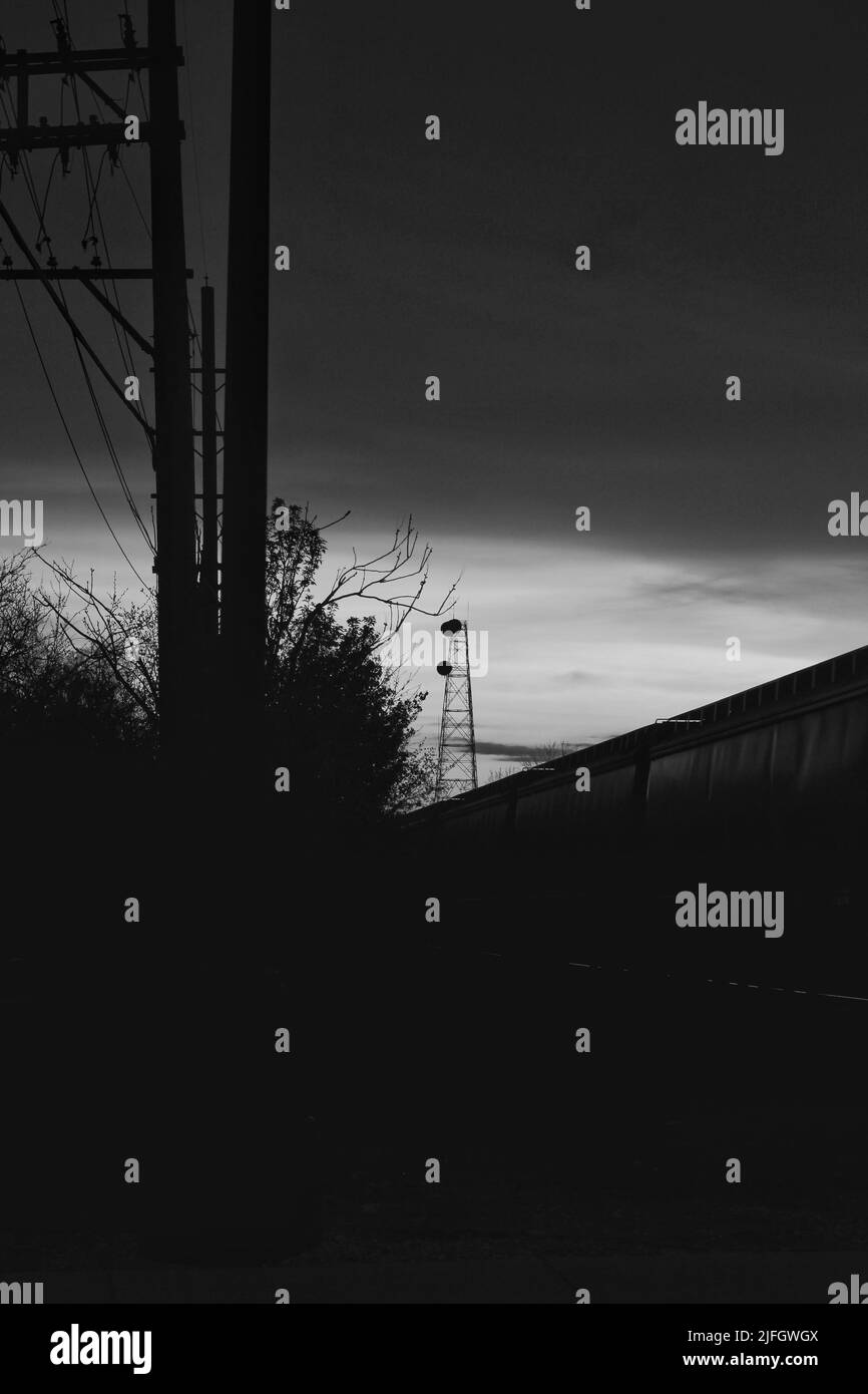 Il cielo di tarda sera si illuminava in bianco e nero dietro le torri di potenza e il complesso industriale. Foto Stock