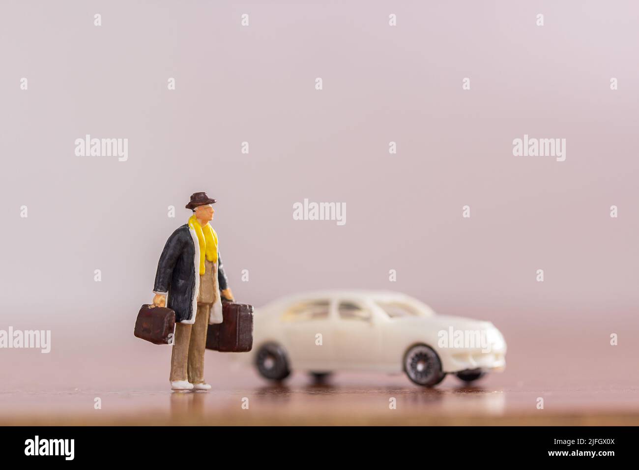Persone in miniatura - borsa da trasporto uomo d'affari in piedi sul pavimento con sfondo bianco offuscato auto. Concetto di viaggio e affari. Foto Stock