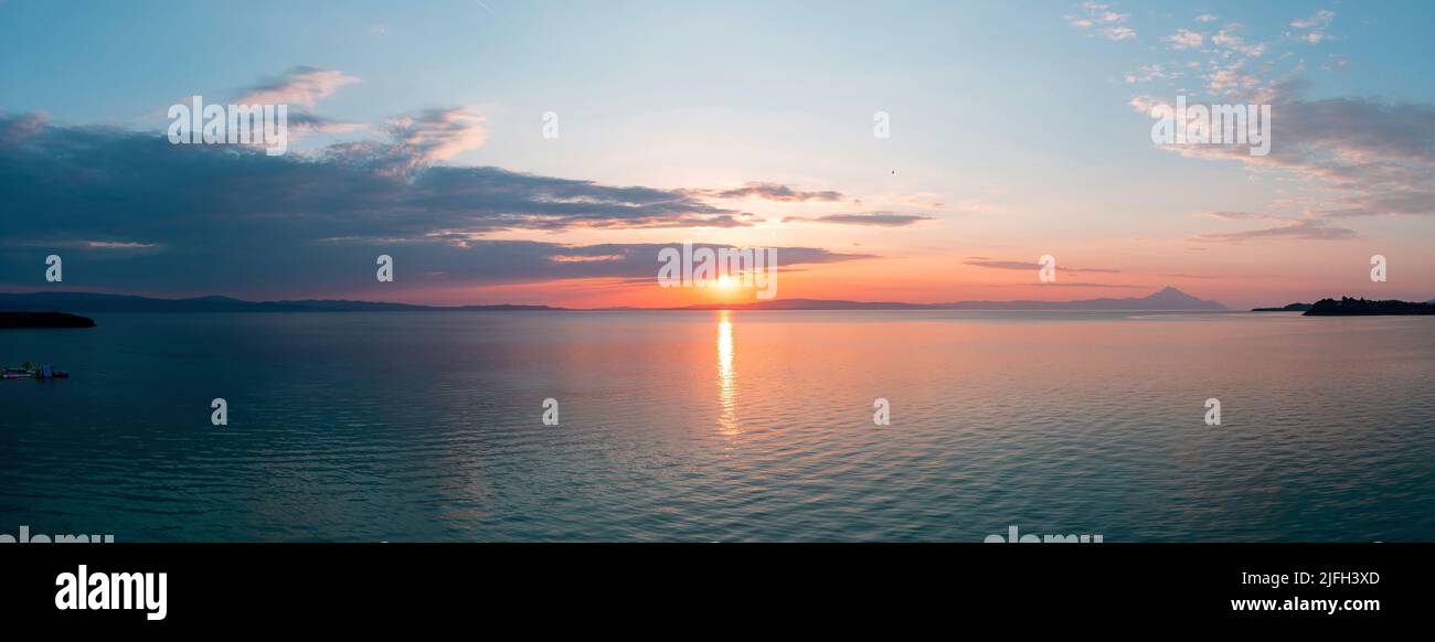 Tramonto sulla tranquilla vista panoramica dell'oceano. Spettacolare e magica alba sul mare Egeo, in Grecia. Sole riflessione sull'acqua. Colore arancione e blu sha Foto Stock