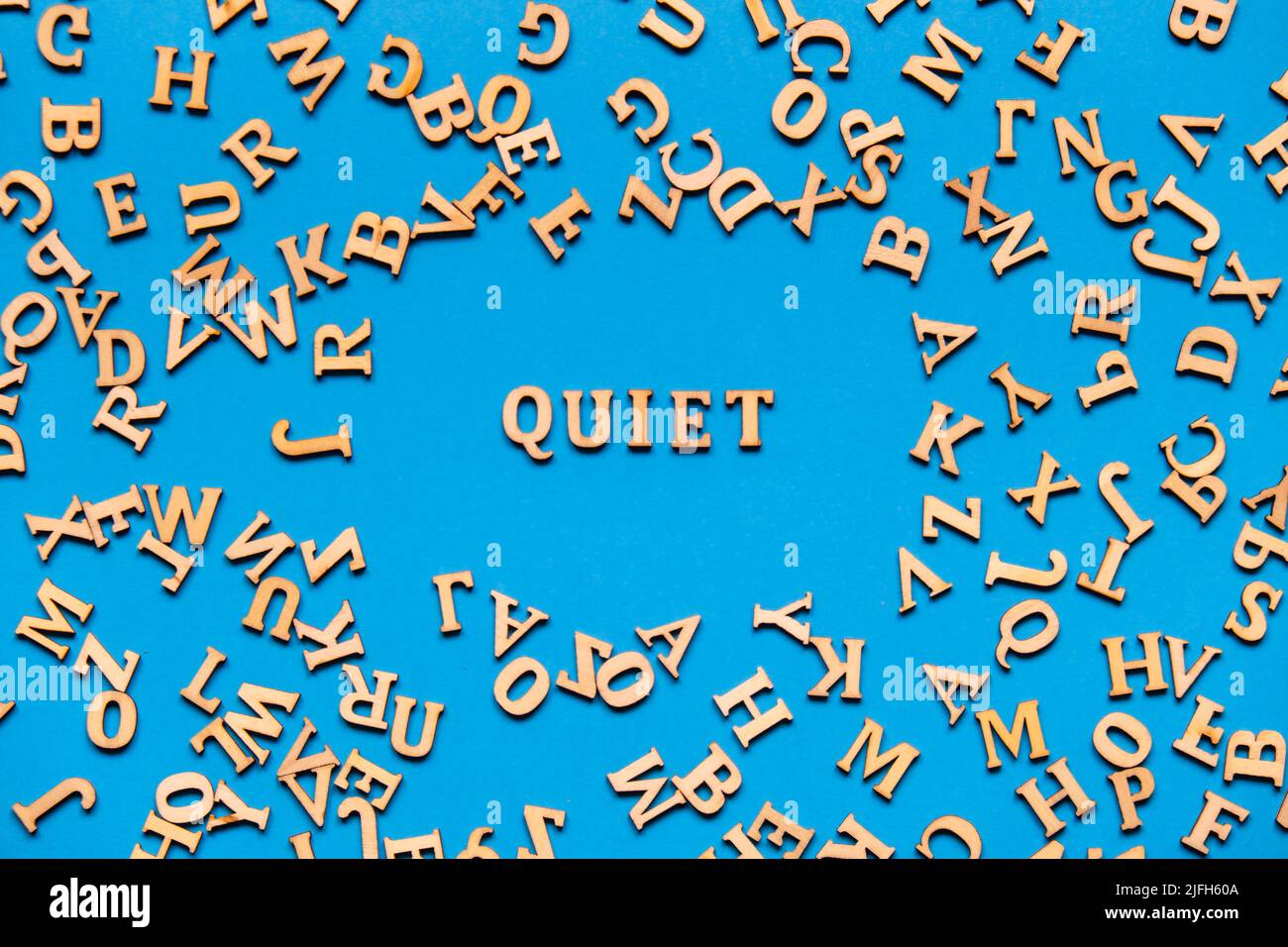 Parola TRANQUILLA fatta di lettere di legno su sfondo blu chiaro. Concetto di citazioni di parole motivazionali. Frase di ispirazione Foto Stock