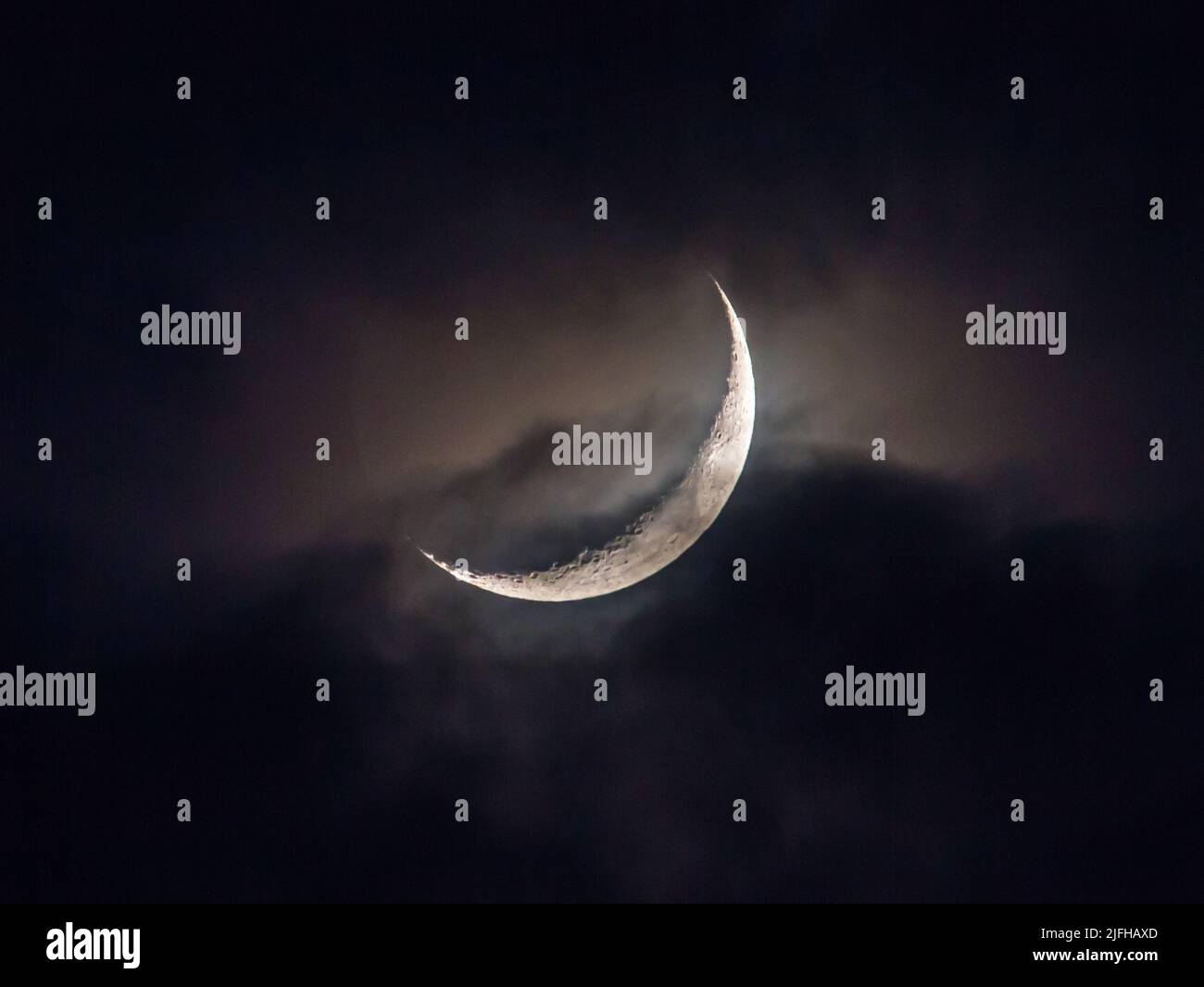 Le nuvole passano una luna crescente di notte. Foto Stock
