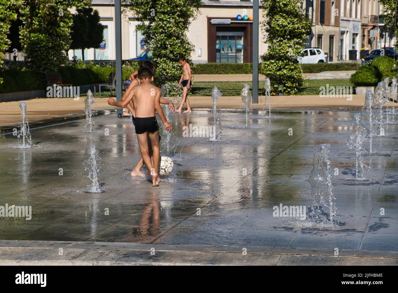 Bambini che giocano a calcio in una piazza fontana in una giornata di sole a Carcassonne Foto Stock