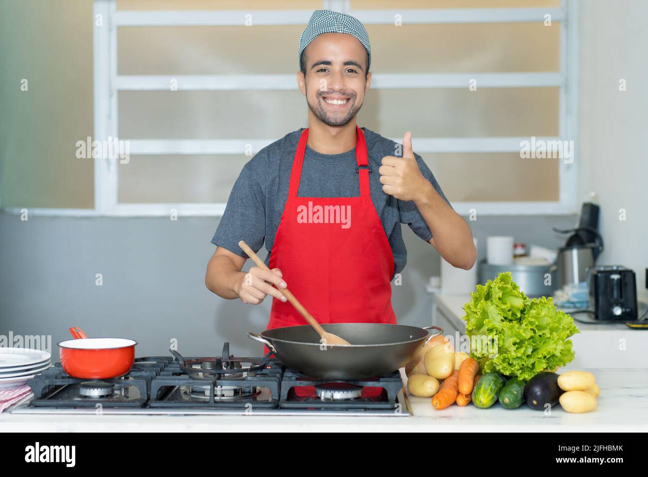 Motivato chef ispanico preparare cibo vegano in cucina del ristorante Foto Stock