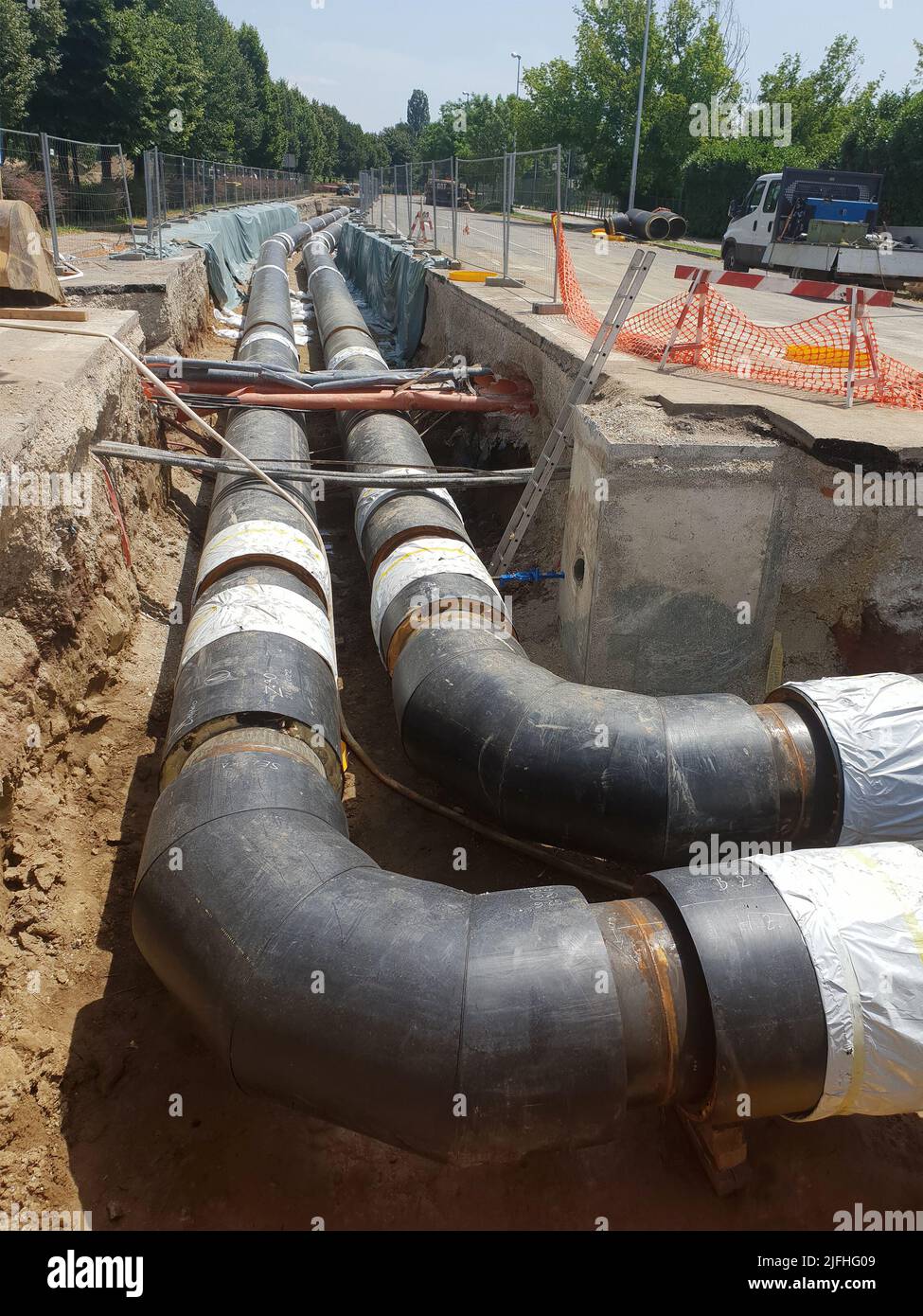 Sito di ricostruzione della pipeline dell'impianto di teleriscaldamento e sostituzione di vecchie tubazioni con nuove. Posa di tubi di riscaldamento in una trincea a costruzione s. Foto Stock