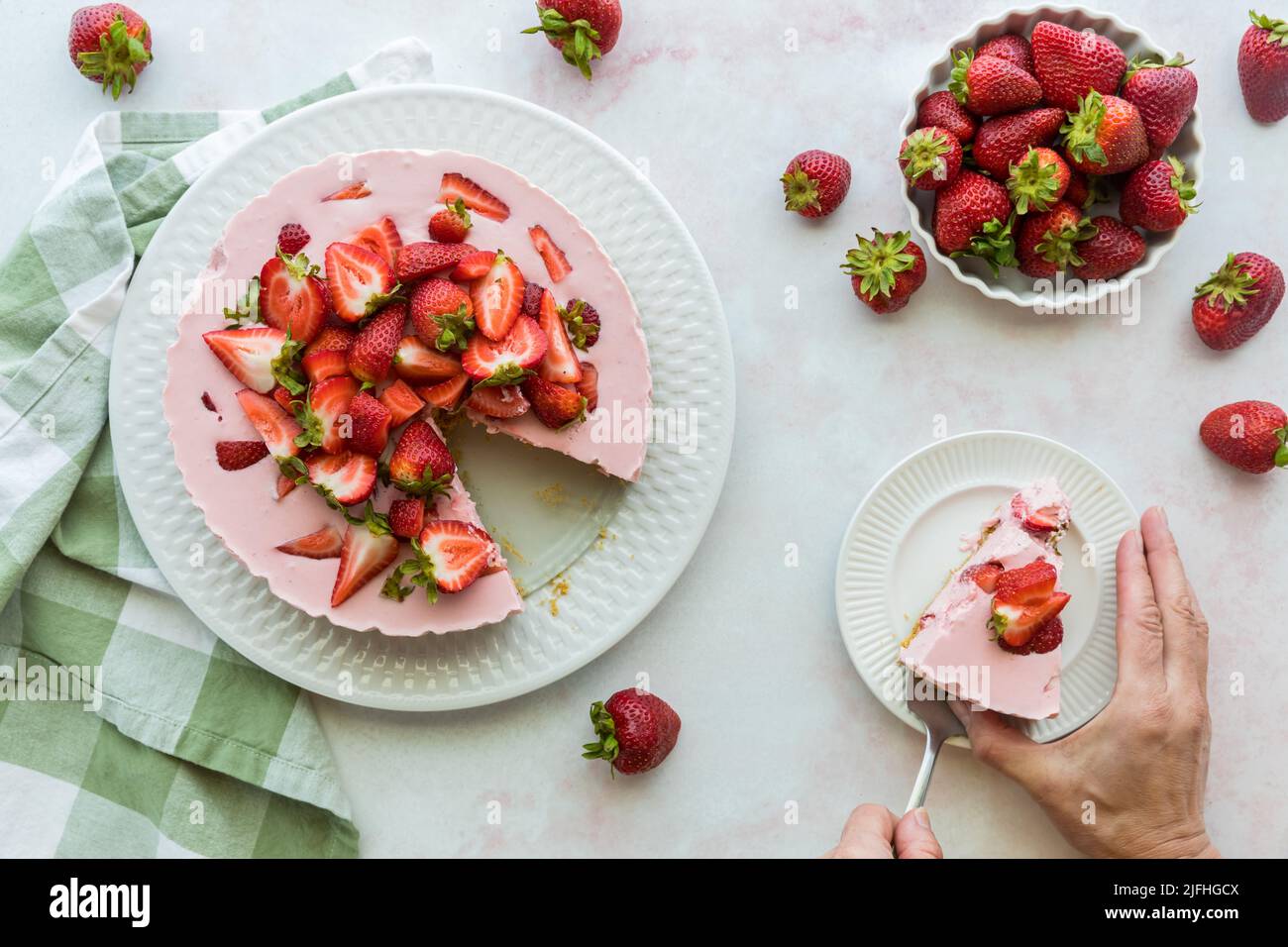 Una bella cheesecake alla fragola con una fetta posta su un piatto. Foto Stock
