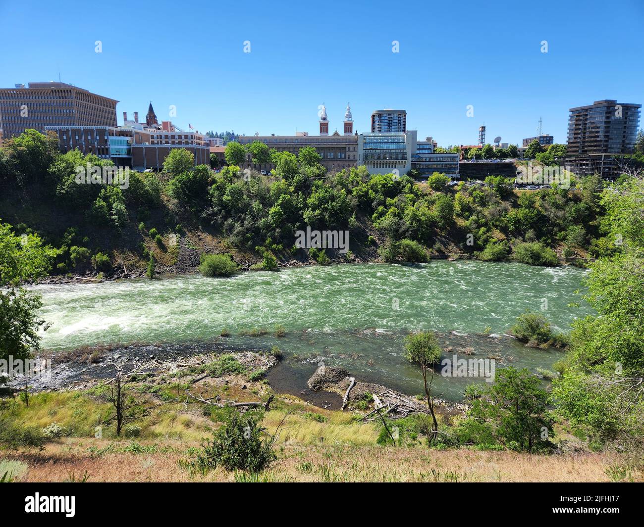 Il fiume Spokane scorre attraverso il centro di Spokane, Washington, in una mattinata estiva limpida e soleggiata. Foto Stock