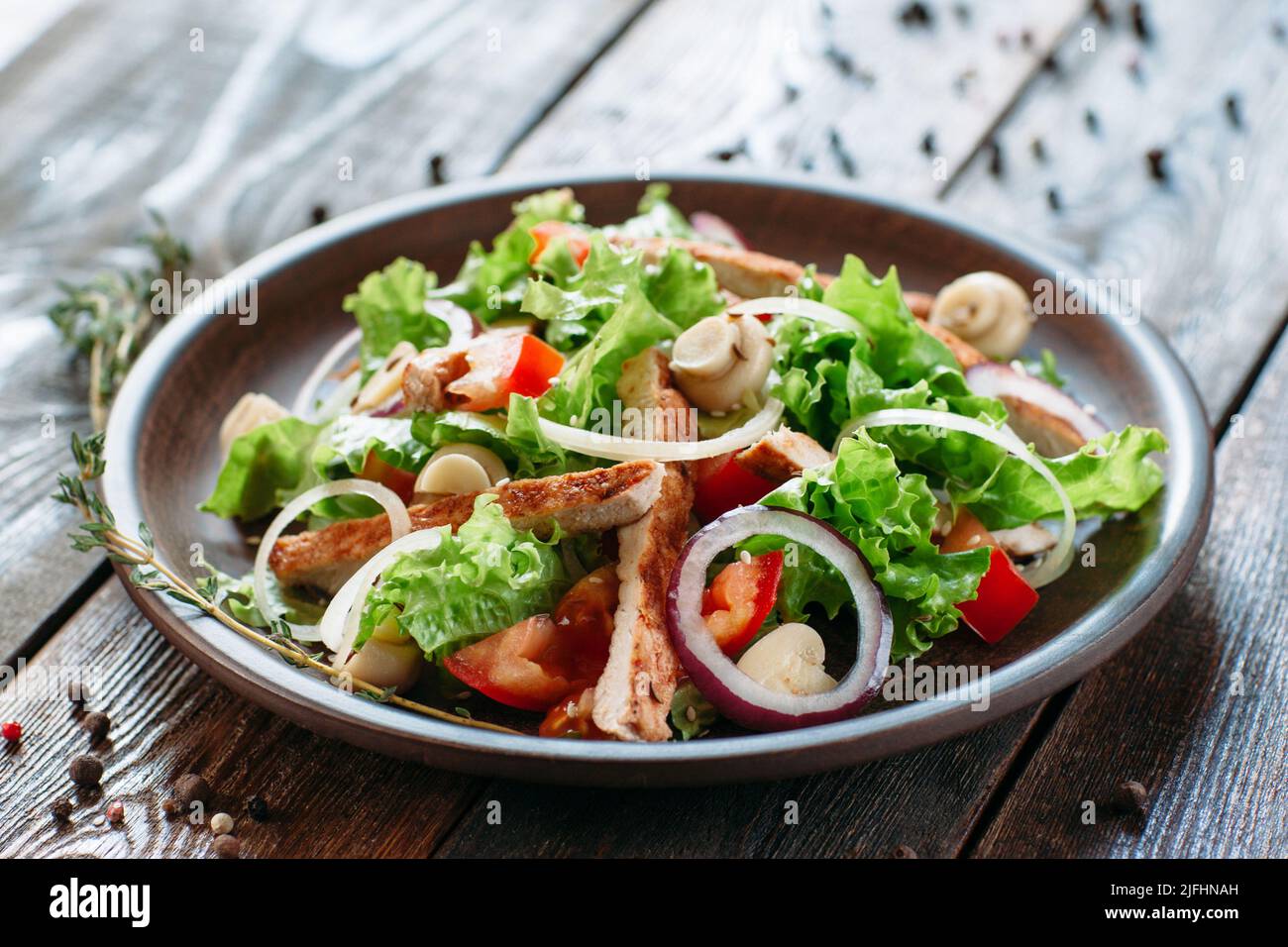 Piatto di argilla con insalata di pollo su tavola di legno Foto Stock