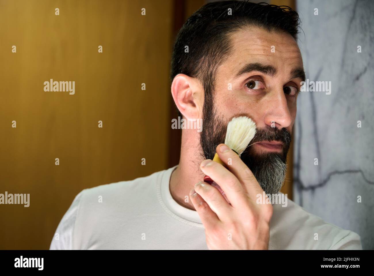 Giovane uomo che gli inzuppava il viso per radersi la barba. Foto di alta qualità Foto Stock