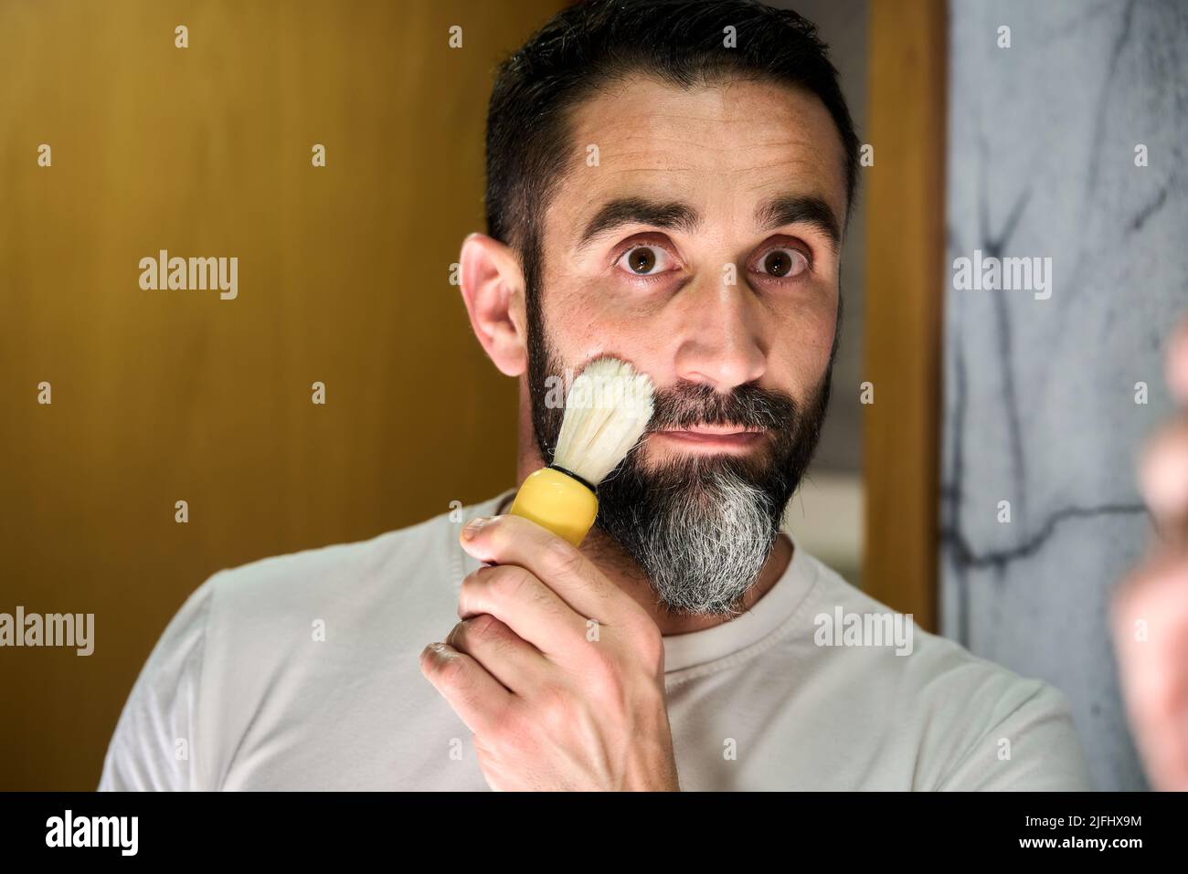 Giovane uomo che gli inzuppava il viso per radersi la barba. Foto di alta qualità Foto Stock