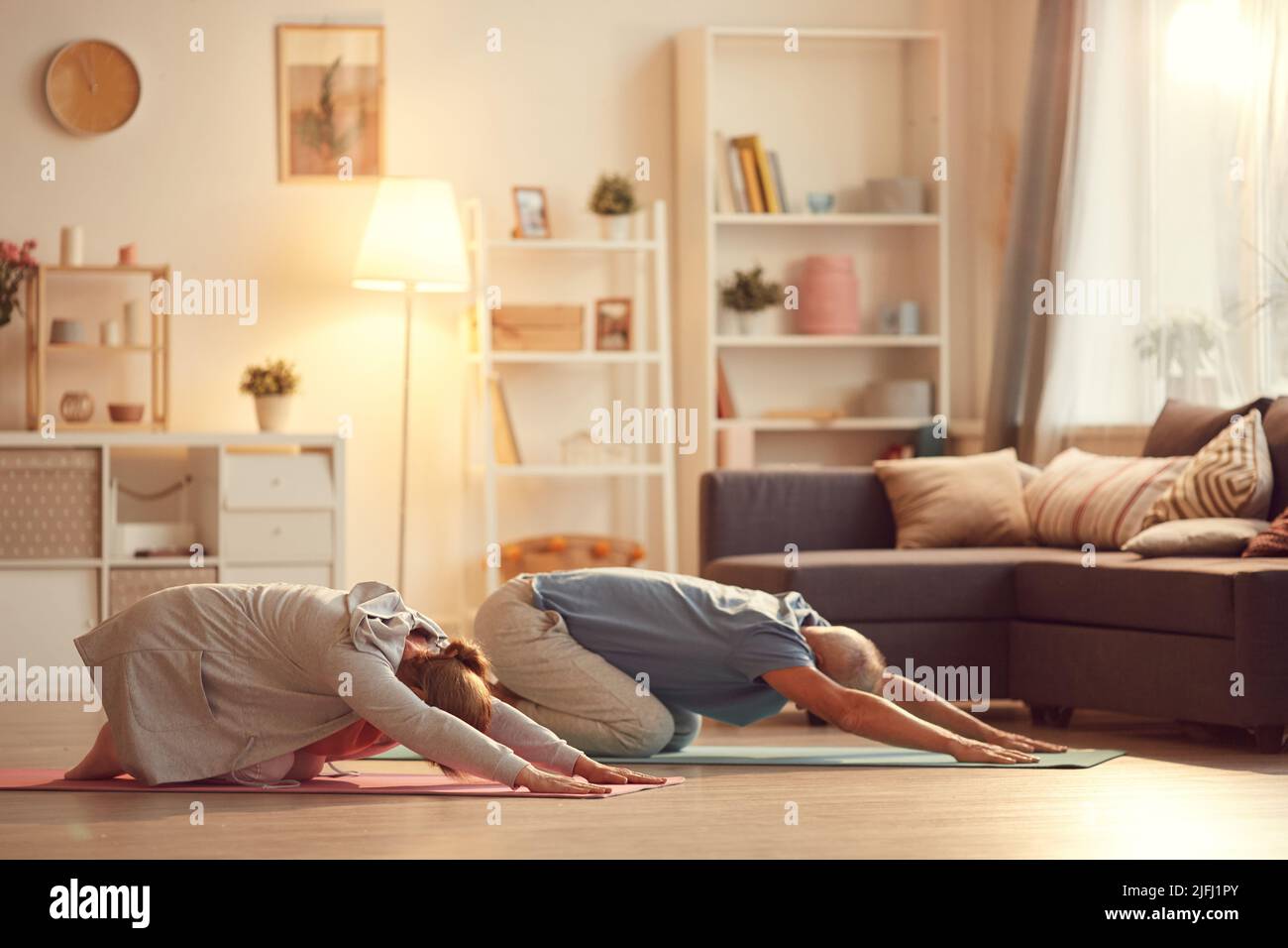 Una coppia matura attiva che riposa in posa per bambini mentre pratichi lo yoga insieme a casa Foto Stock
