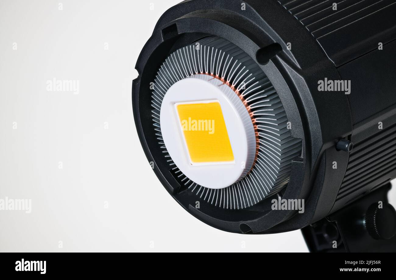 Modulo LED giallo in riflettore fotografico con alette di raffreddamento in alluminio su sfondo bianco. Luce elettrica ad alta potenza nera proveniente da diodi a semiconduttore. Foto Stock
