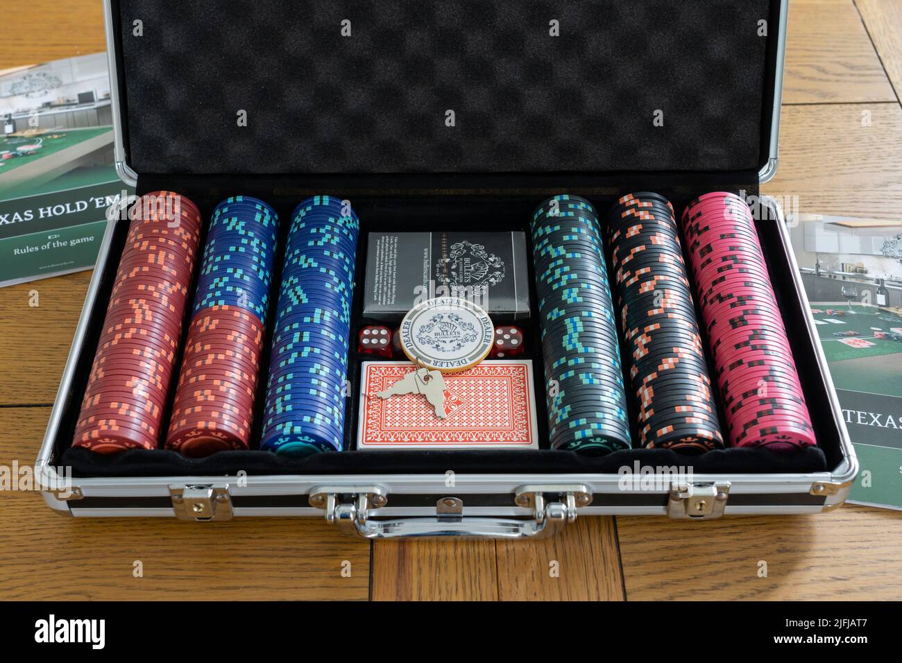 Un caso di poker metallico con chip scommesse, pacchetti di carte da gioco e un gettone del mazziere per giocare Texas Hold 'em. Tema - poker, gioco d'azzardo a casa Foto Stock