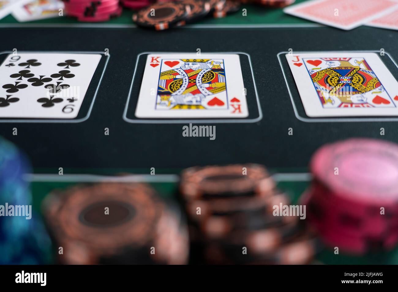 Primo piano delle carte da gioco e delle fiche di scommessa di poker su un mat di poker. Concetto - strategia di poker, gioco d'azzardo, scommesse, dipendenza da gioco d'azzardo, il flop Foto Stock