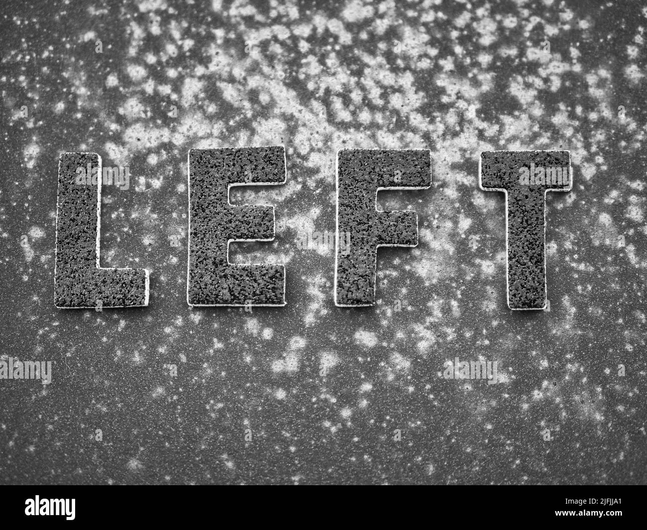 La parola 'a sinistra' in lettere nere su una superficie di metallo arrugginita nera. Foto Stock
