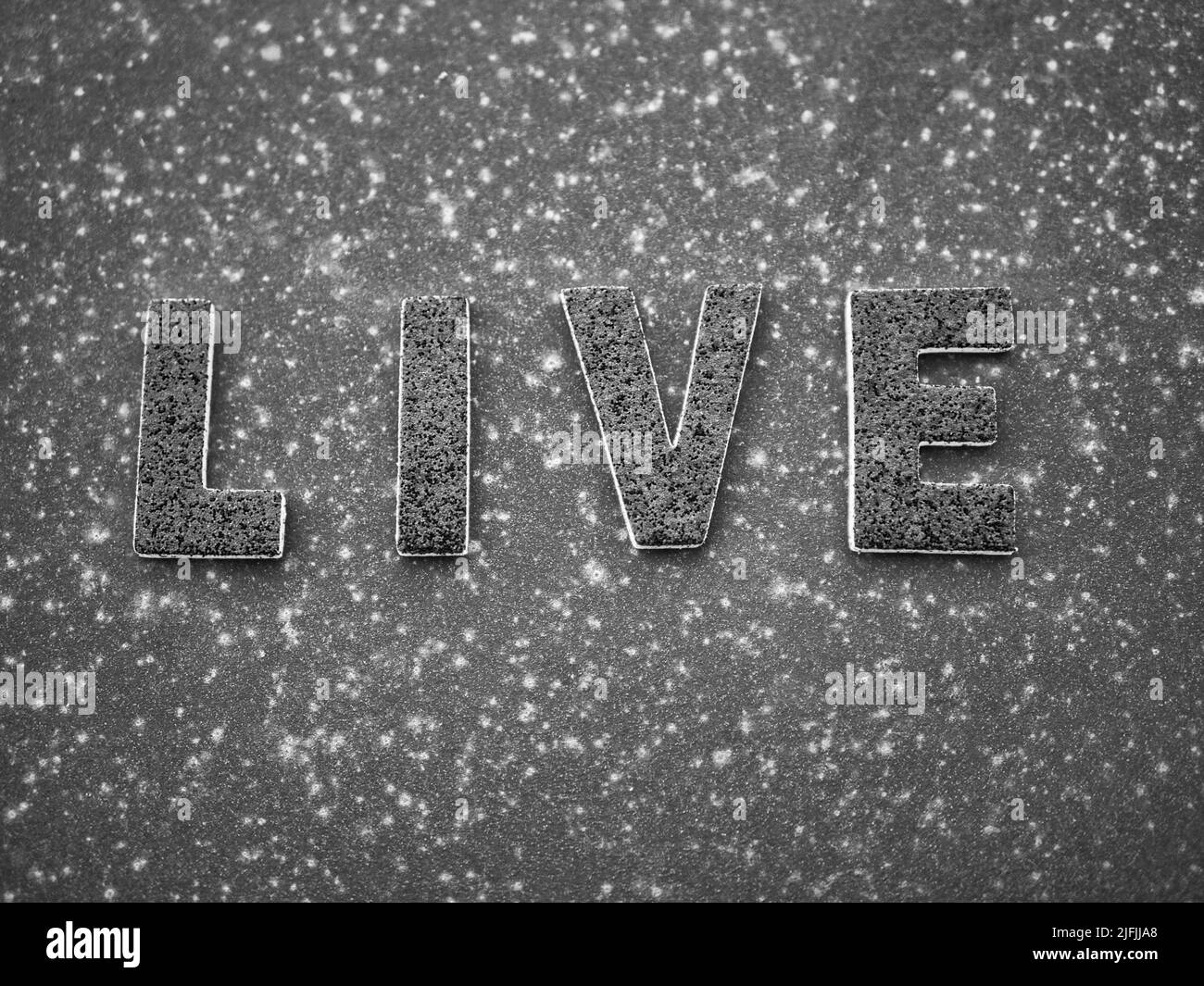 La parola 'Live' in lettere nere su una superficie in metallo arrugginito nero. Foto Stock
