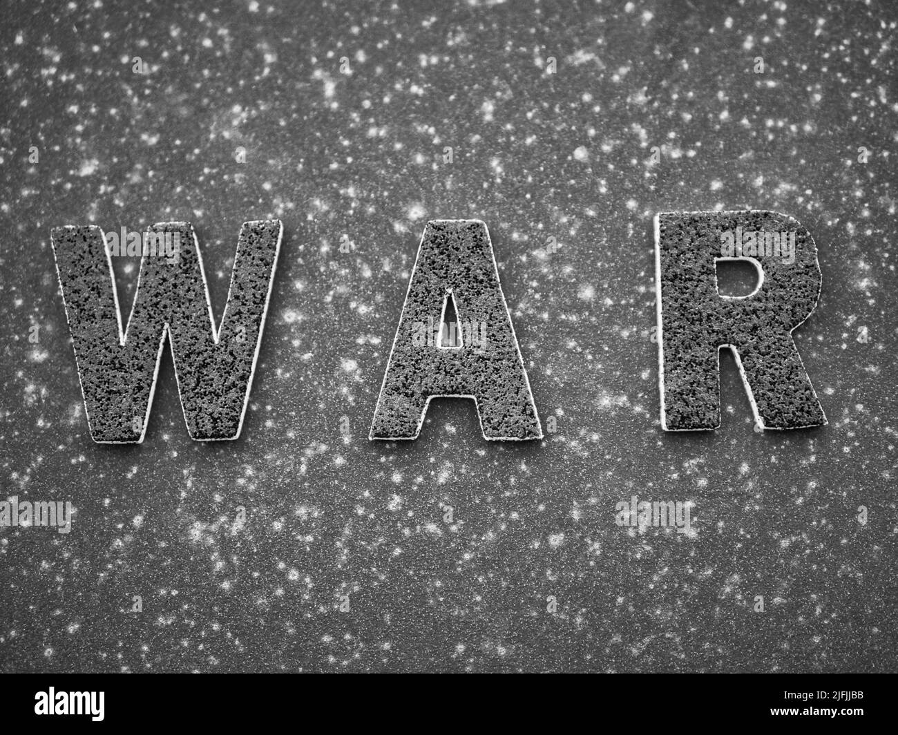 La parola 'Guerra' in lettere nere su una superficie di metallo arrugginito nero. Foto Stock