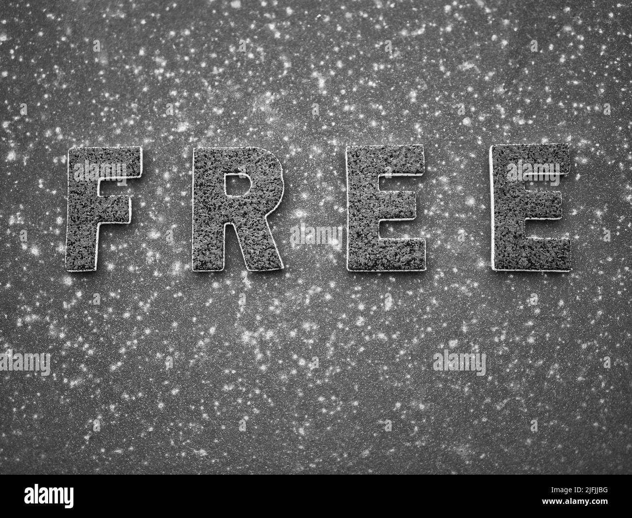 La parola 'libero' in lettere nere su una superficie di metallo arrugginito nero. Foto Stock