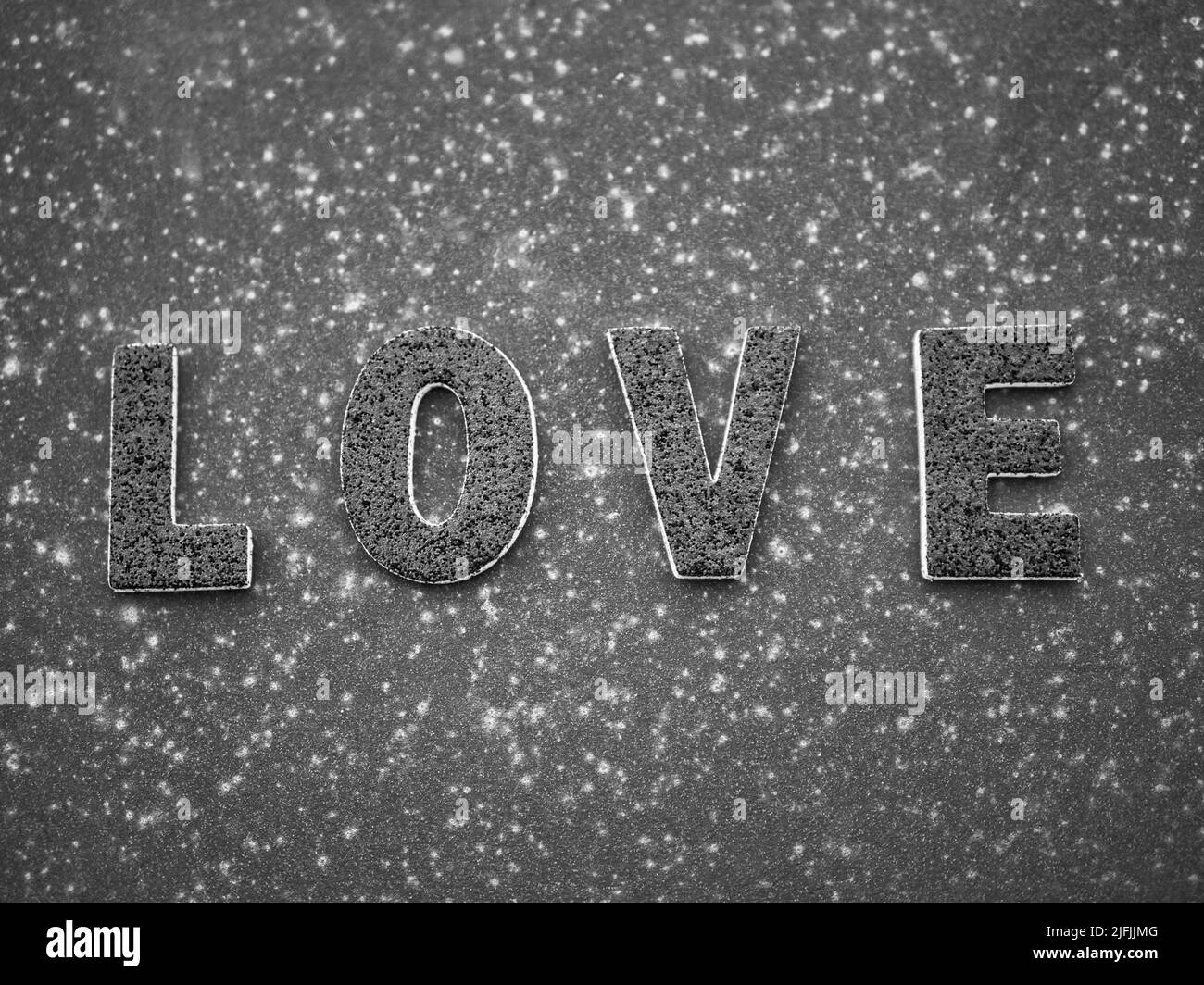 La parola 'Amore' in lettere nere su una superficie di metallo arrugginita nera. Foto Stock