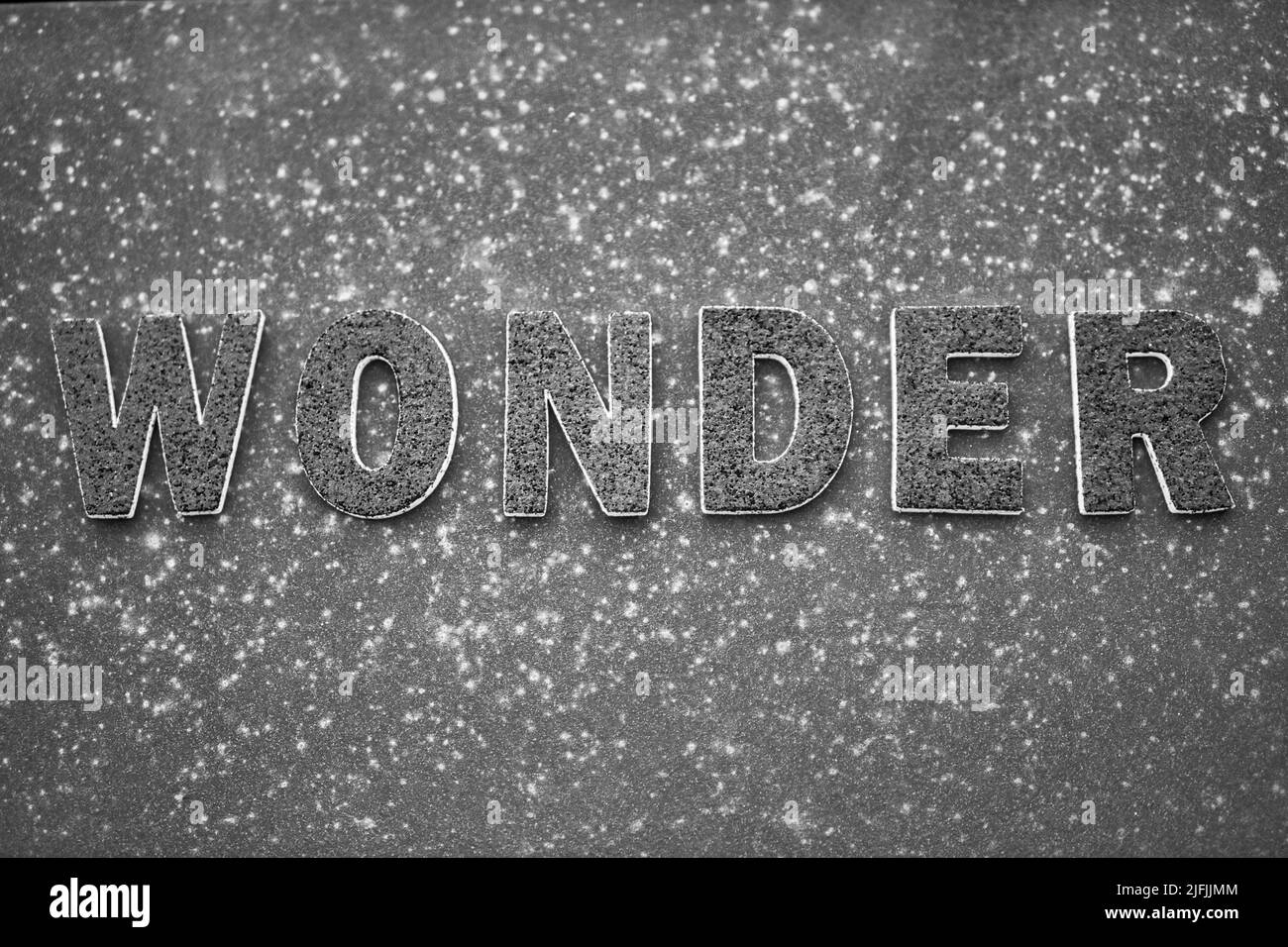 La parola 'Wonder' in lettere nere su una superficie di metallo arrugginita nera. Foto Stock