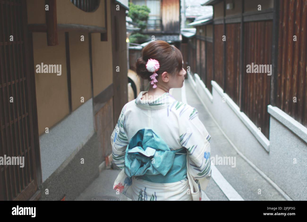 La parte posteriore di una donna giapponese, camminando su una vecchia strada stretta a Kyoto, Giappone indossando uno yukata Foto Stock