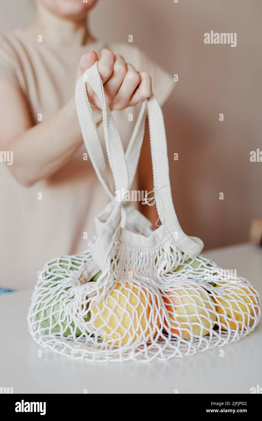 La ragazza sta tenendo una borsa eco-consapevole piena di frutta. Foto Stock