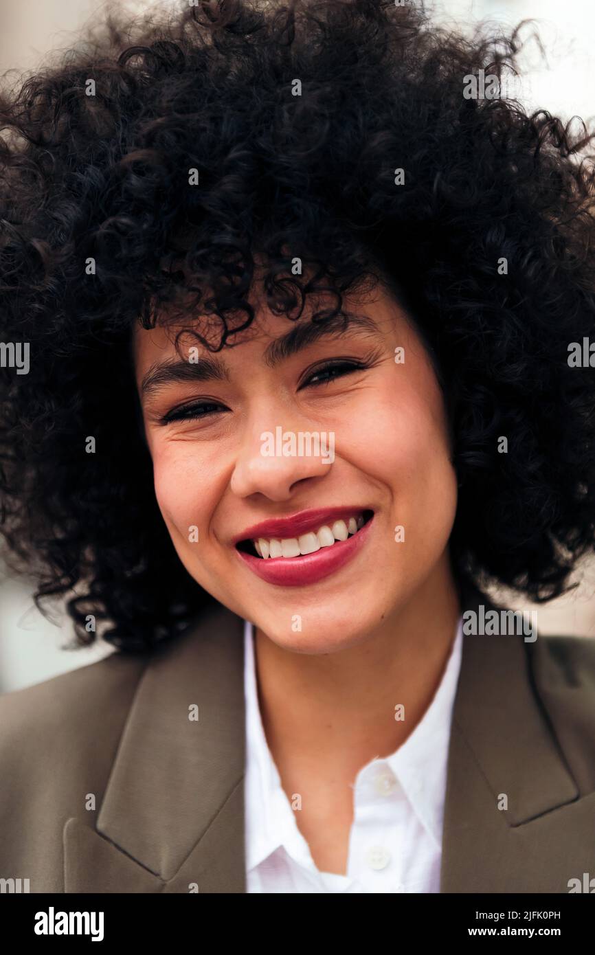 giovane donna latina sorridente con capelli ricci Foto Stock