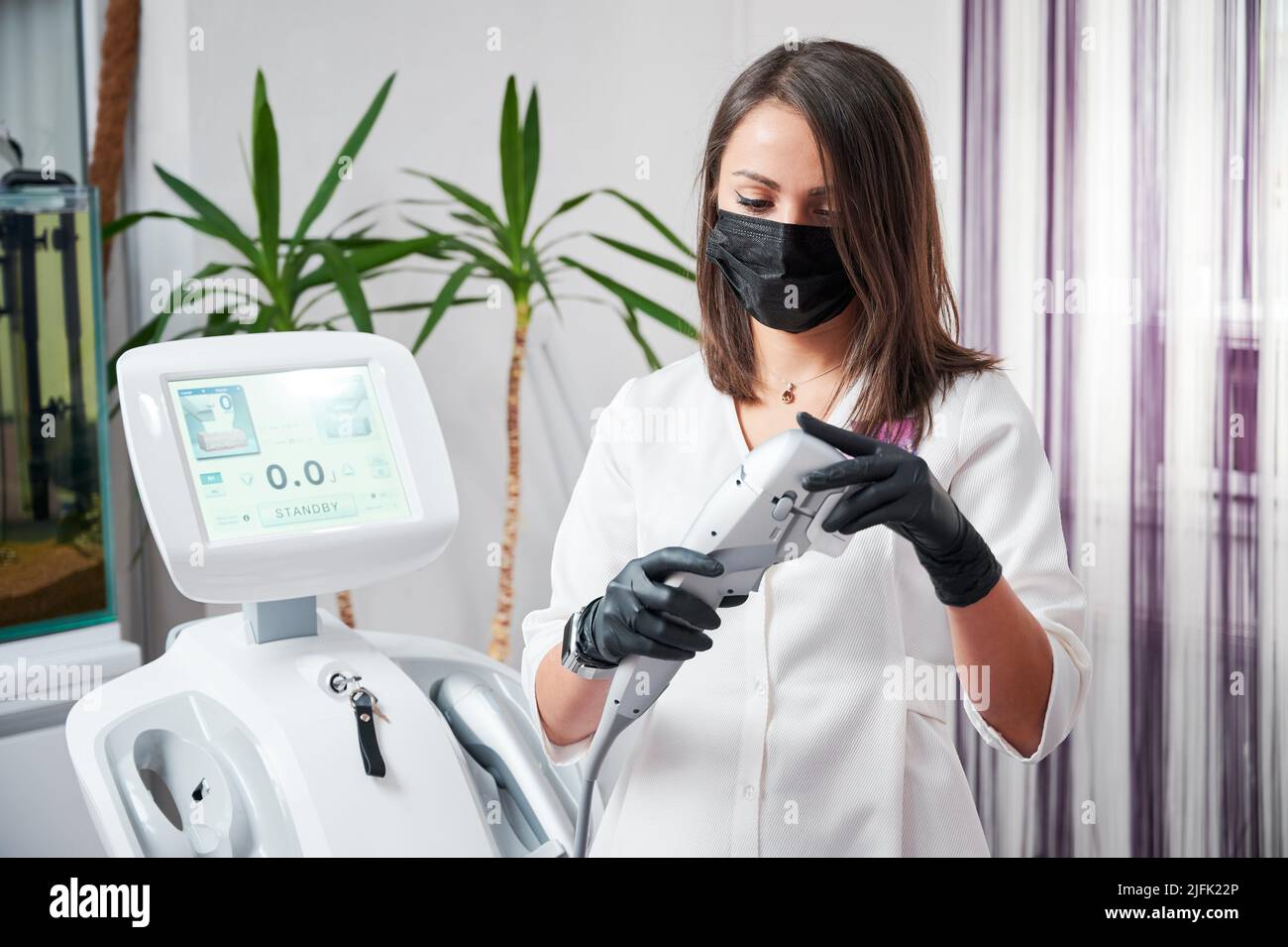 Clinica di medicina estetica. Cosmetologo in maschera protettiva e guanti dispositivo di preparazione per la ricezione di pazienti che hanno assegnato la procedura SMAS sollevamento da ultraformer. Foto Stock