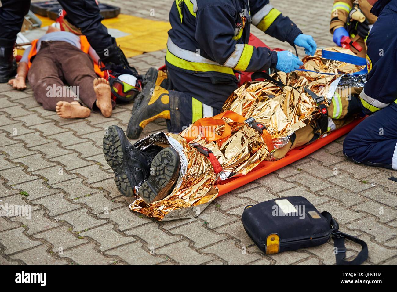 I soccorritori forniscono il primo soccorso alla vittima durante un incidente stradale. La persona ferita nell'incidente è sdraiata sulla strada Foto Stock