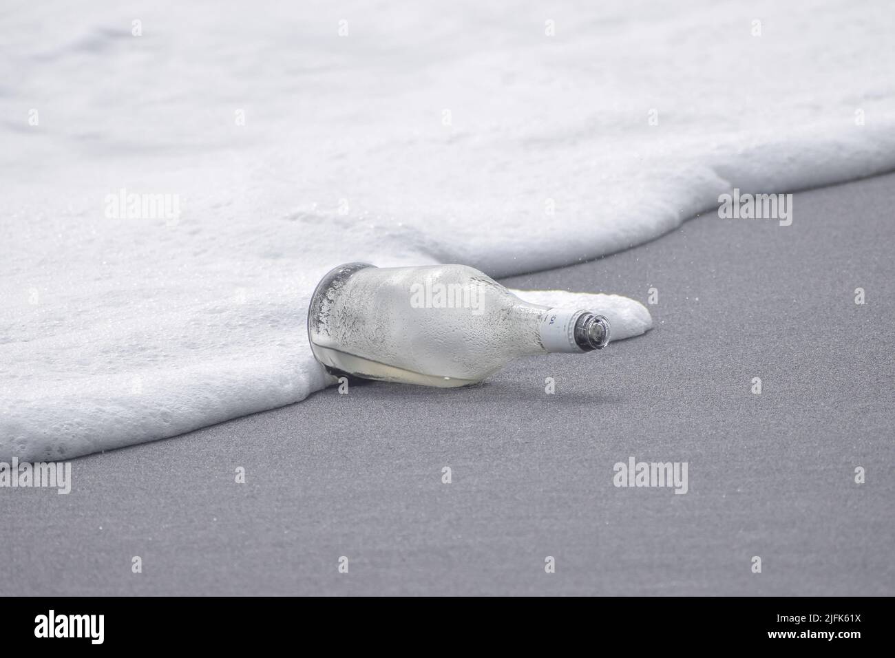 Una bottiglia di vetro si trova in riva al mare . Concetto - rifiuti marini e messaggi. Foto Stock