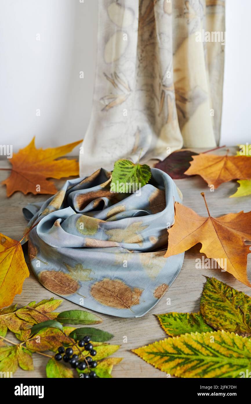 Sciarpe di seta tinte a mano circondate da bacche e foglie d'autunno. Tecnica eco-print Foto Stock